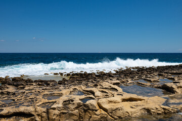 Sea waves crashing on traditional rock cut Roman baths in Sliema Malta © Aleksandar