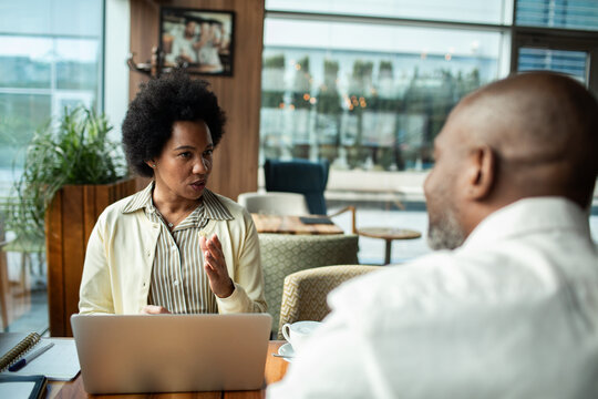 Woman explaining to man at cafe table