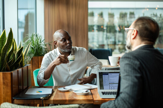 Two businessmen discussing work over coffee in a cafe