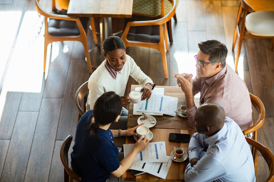 Coworkers discussing reports over coffee in a cafe