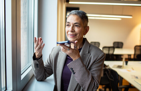 Senior businesswoman sending a voice message in office