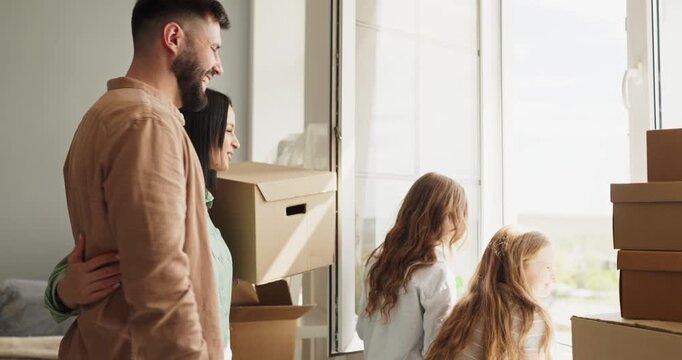 Family parents children moving boxes home happiness. They smile by a bright window with cartons, eager for a fresh start and teamwork in their new home. Clear concept of happy family relocation.