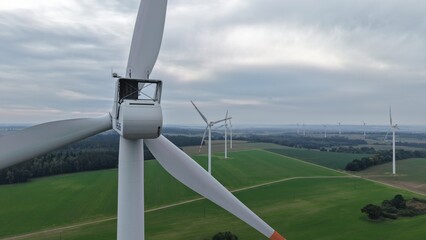 duże białe wiatraki elektrownie wiatrowe turbiny wiatrowe stojące na tle krajobrazu rolniczego © Adam Schmidt