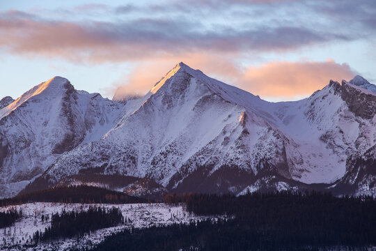 Majestic panoramic view of the Tatra Mountains landscape featuring snow-capped peaks, colorful forests, and picturesque valleys under a dramatic sky. Beautiful scenic nature and wilderness background