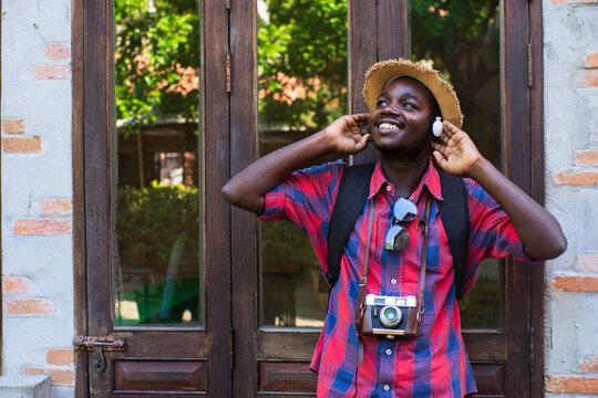 Happy African Male Tourist Enjoying Music with Earphones Near Vintage Building