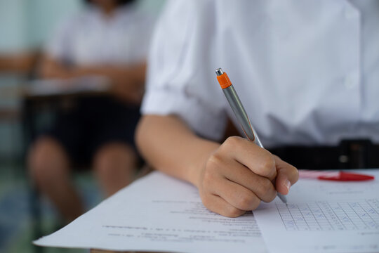 Close-up of Student Hand Writing on Exam Paper with Pen
High School Student Taking Standardized Test with Concentration on Wooden Desk