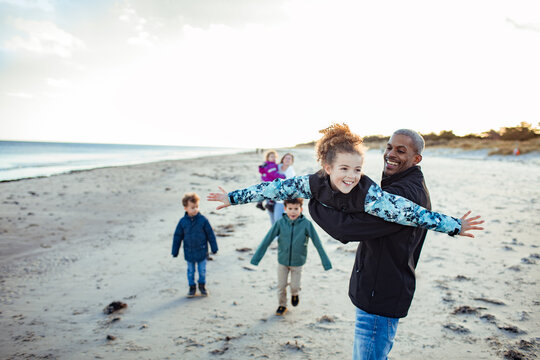 Man lifting girl like an airplane on the beach