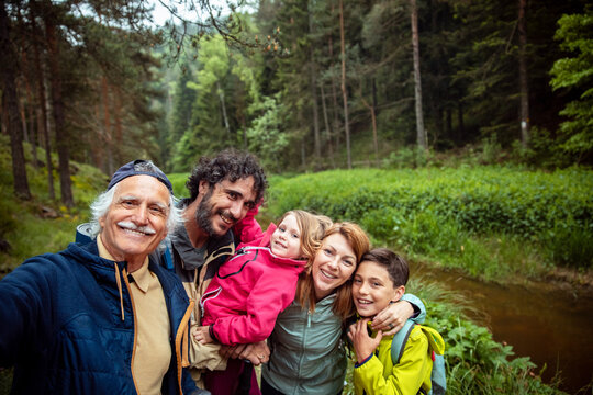 Happy family taking hiking selfie by forest stream