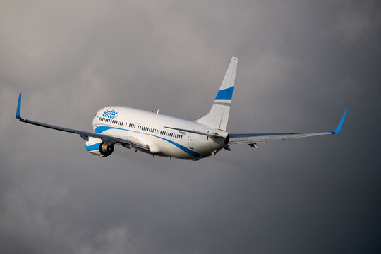 Side rear view of Enter Air Boeing 737 airplane climbing into dark cloudy sky in Gdansk, Poland