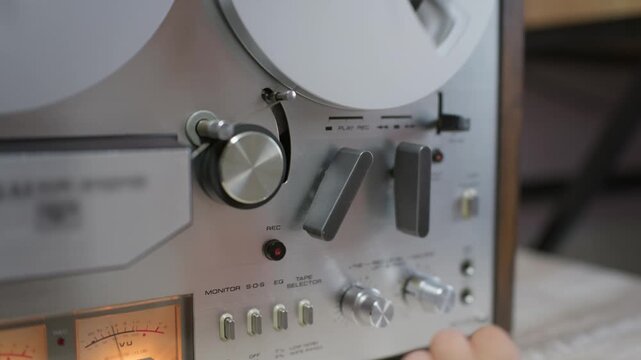 A young child operates mechanical levers and knobs on a vintage reel-to-reel tape recorder. Tactile controls and spinning metal reels offer authentic nostalgia for music storytelling.