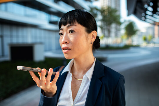 Businesswoman using voice command on smartphone outdoors