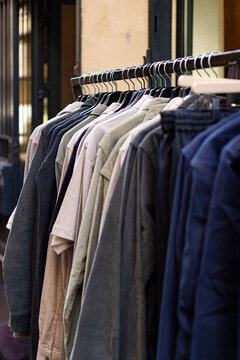 Clothing hangs on metal hangers along an outdoor retail rack in Montpellier, France. Shirts and jackets are displayed for sale outside a local boutique shop in the city center.