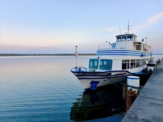 A passenger excursion boat is moored at a concrete pier on Quiet Lake late in the evening. © Irina