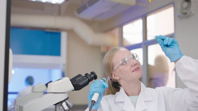 Female Scientist Examining Liquid Sample with Pipette and Microscope in Medical Cosmetic Laboratory for Innovative Scientific Research and Clinical Healthcare Discovery