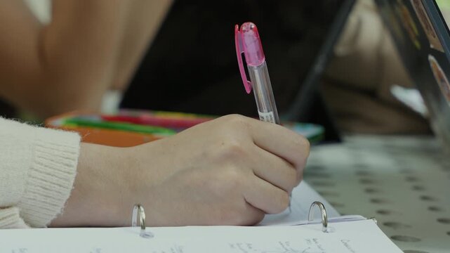Student's hand writing notes in a binder notebook