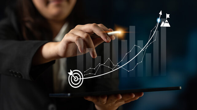 A businesswoman interacts with financial graphs on a tablet, representing data growth and success strategies in a professional office environment. Ledger