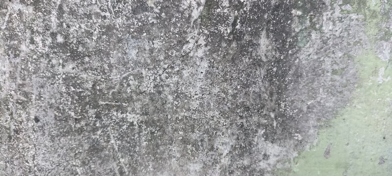 Plaster wall texture with peeling paint fragments, weathered grey surface, and faint pale green tones, great for vintage restoration projects and grunge backgrounds