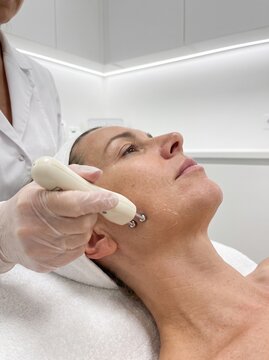 Patient receiving skin tightening facial treatment with microcurrent device in a beauty clinic