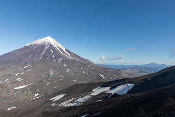 Majestic view of Koryaksky stratovolcano with snow and volcanic slopes against a clear blue sky in Kamchatka Krai, Russia, showcasing the wild and remote subarctic wilderness © TravelFlow