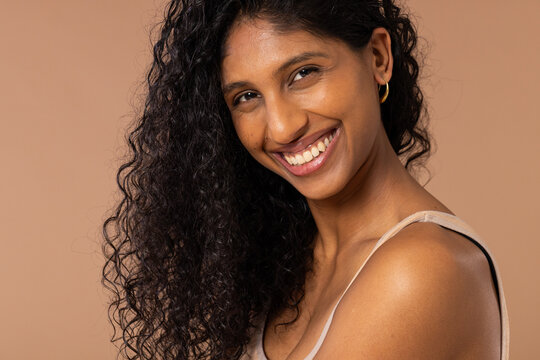 African American woman smiling and posing in studio with gold hoop earring and visible bra strap