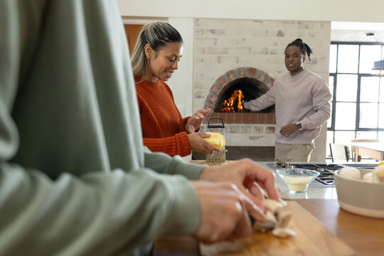 Diverse friends chopping mushrooms, grating cheese, tending brick oven in rustic kitchen