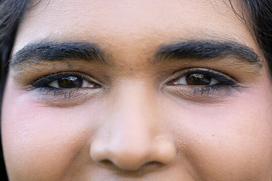 Indian woman facing camera in extreme closeup showing eyeliner, mascara and beauty mark