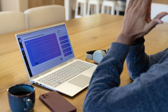 Indian man blue sweater working on laptop with digital marketing, mug phone at workspace