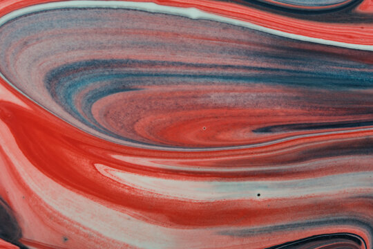 Fluid art background with swirling patterns red, blue, and white paint.