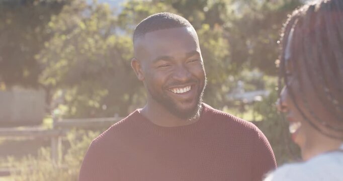 Couple with African American man in maroon sweater laughing, responding to partner's joke outdoors