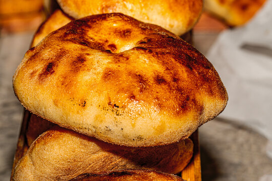 Freshly baked homemade pita bread pockets on a rustic kitchen board.