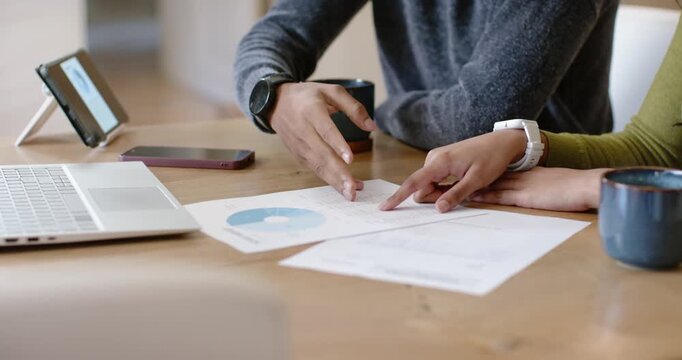 Indian colleagues sitting at home table, starting with printed blue pie chart, planning next steps