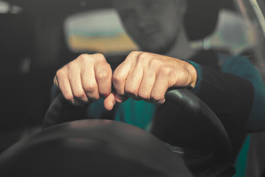 Closeup of Driver Holding Steering Wheel with Both Hands. Close-up of a man's hands gripping a black steering wheel inside a car, highlighting driving control, road safety, and responsible vehicle han