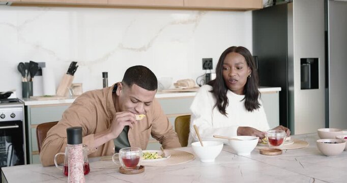 African American couple at island man offering bite to share woman declining sharing tea leaning