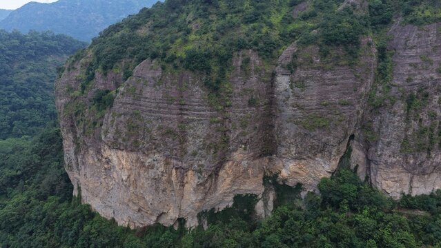 Aerial view of towering karst mountains in Lingfeng, Yandangshan, China, with a traditional temple nestled below. Dramatic limestone peaks and lush vegetation dominate the landscape.