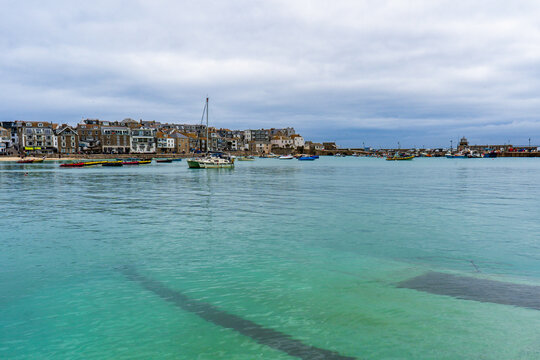 St Ives Harbour, Cornwall, during high tide with boats and clear emerald water.