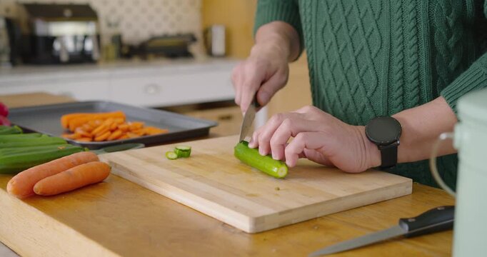 Hands are placing zucchini and picking knife, steadying slicing rounds on board at counter for meal