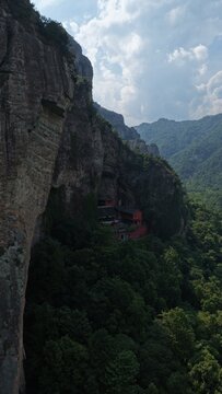 Aerial view of towering karst mountains in Lingfeng, Yandangshan, China, with a traditional temple nestled below. Dramatic limestone peaks and lush vegetation dominate the landscape.