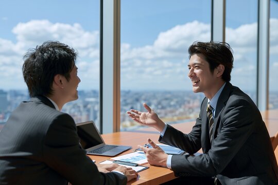 笑顔のビジネスマンが高層ビルを望む会議室で打ち合わせを行う