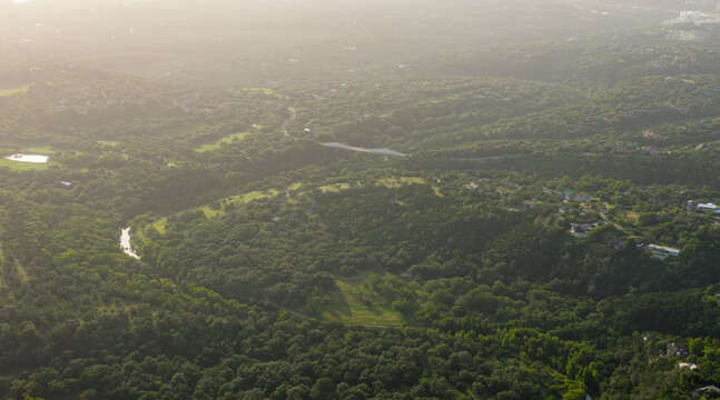 Aerial telephoto of Barton Creek Bridge at sunset over lush Austin Hill Country