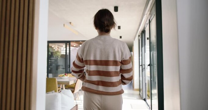 Female in sweater after delivery, carrying labeled box into kitchen, opening to inspect items