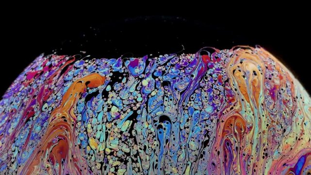 Soap bubble starting to loose cohesion as fragmentation shows up and really thin black of film layer going up and accumulation at the top of the bubble.