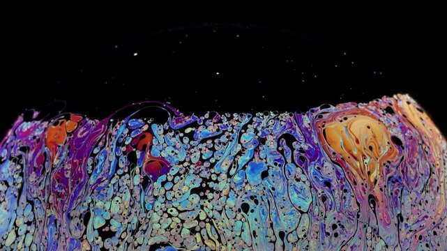 Soap bubble starting to loose cohesion as fragmentation shows up and really thin black of film layer going up and accumulation at the top of the bubble.