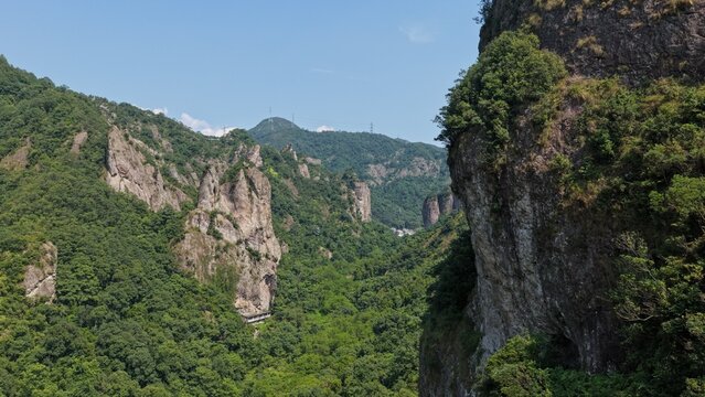 Aerial view of towering karst mountains in Lingfeng, Yandangshan, China, with a traditional temple nestled below. Dramatic limestone peaks and lush vegetation dominate the landscape.