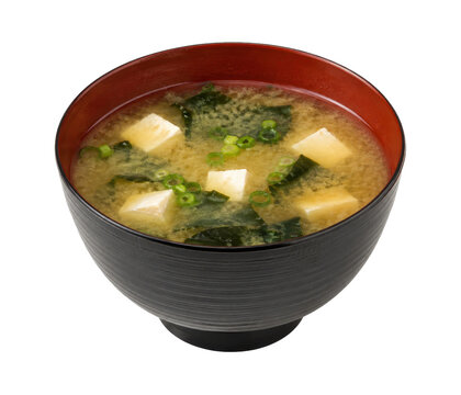 Traditional Japanese miso soup with tofu, seaweed, and chopped green onions in a black and red bowl, isolated on white