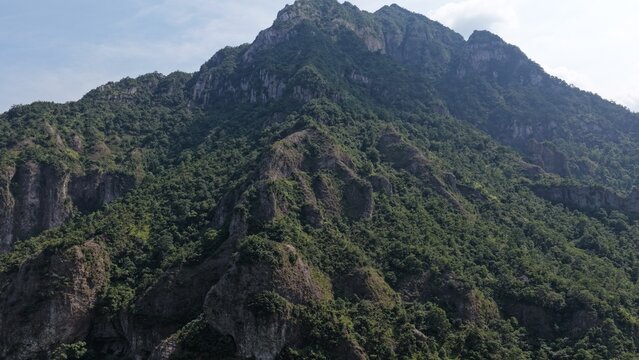 Aerial view of towering karst mountains in Lingfeng, Yandangshan, China, with a traditional temple nestled below. Dramatic limestone peaks and lush vegetation dominate the landscape.