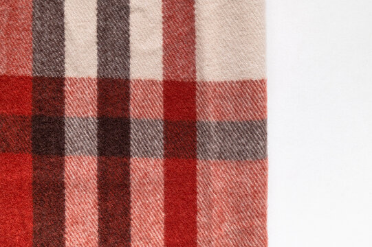 Seasonal plaid fabric shows red, gray and beige checks in detailed close view with clean background space. Woven pattern fits autumn fashion campaigns, textile catalogs and clothing design concepts.