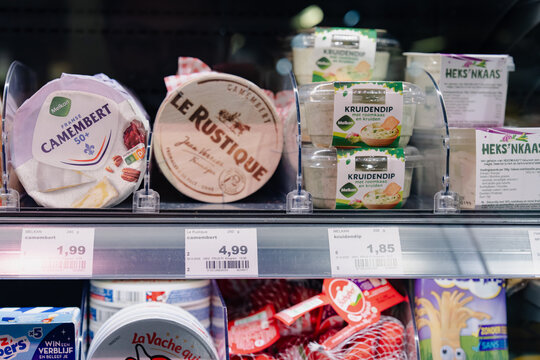 September 24, 2026, Amsterdam, Netherlands - Supermarket shelf displaying various cheese and dip products, including Melkan Camembert, Le Rustique Camembert, Melkan Kruidendip, and Heks'nkaas.