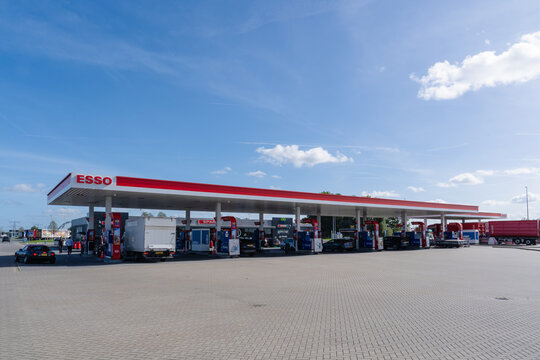 September 24, 2026, Amsterdam, Netherlands - Esso gas station with vehicles and people under a blue sky