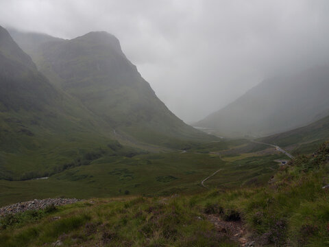 Misty late summer weather view down Glencoe in the highlands of Scotland, showing slopes of Gearr Aonach, Coire nan Lochan and Aonach Dubh, the valley floor and very misty Aonach Eagach.