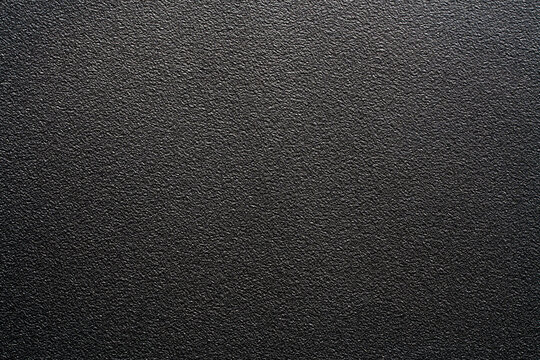 Black plastic texture full frame abstract rough dark background. Top view dark grey matte textured surface. Black grainy powder coated metal, industrial plastic or asphalt for modern design
